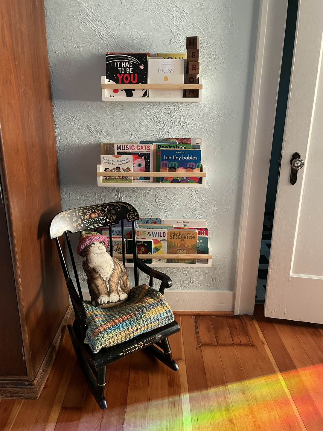 reading nook with secondhand child-size wooden rocker, plastic-free book storage, mom's childhood cat stuffylovey, and grandma's crochet blanket